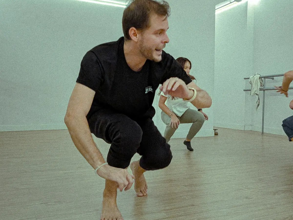 Iñigo Zubiri, agachado, muestra un ejercicio de cuerpo en una clase de teatro para adultos en Madrid