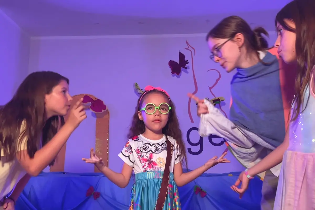 Alumnas de la escuela en escena, con vestuario y luz de escenario, en una muestra
