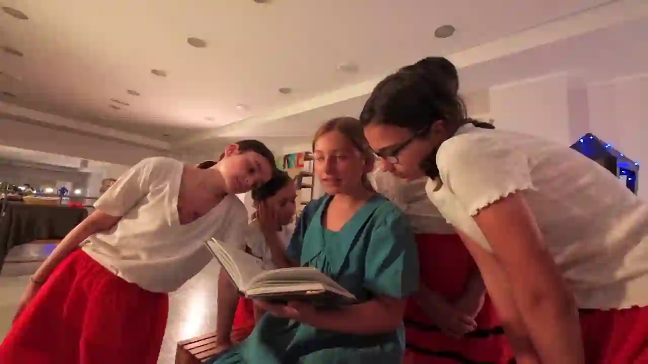 Alumnas de la escuela con un libro en escena, en una muestra de Escena Zero